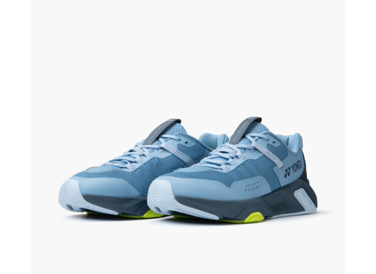 Blue Yonex athletic sneakers with mesh upper and lime-green outsole details, shown from a side angle on a white background.