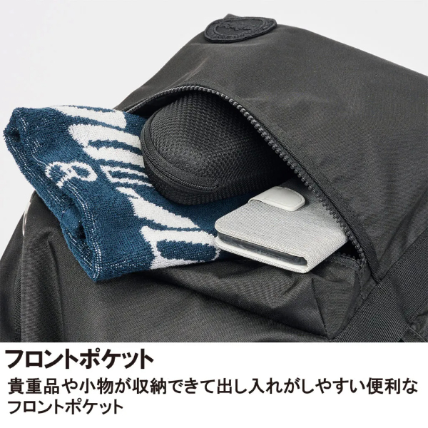 Front pocket of a black backpack with a towel and a phone tucked inside, illustrating easy-access storage for valuables and small items.