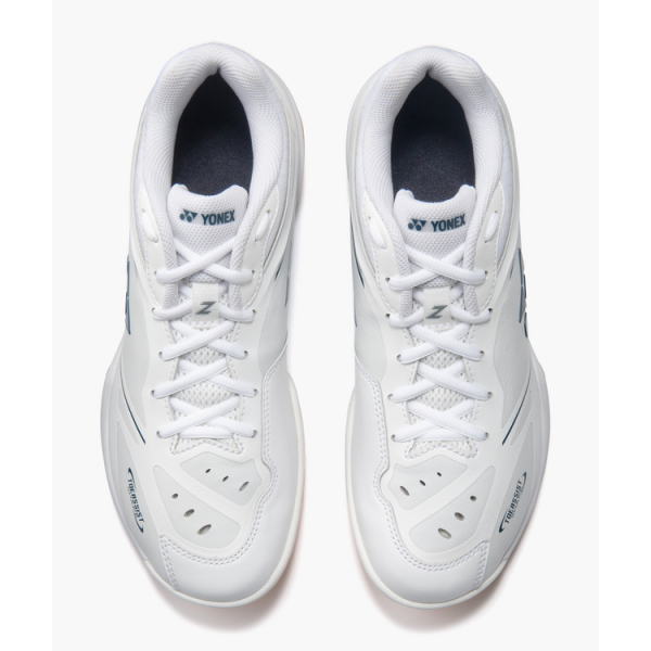 Pair of white Yonex badminton shoes viewed from above, laces tied, showing blue interior lining and grip soles