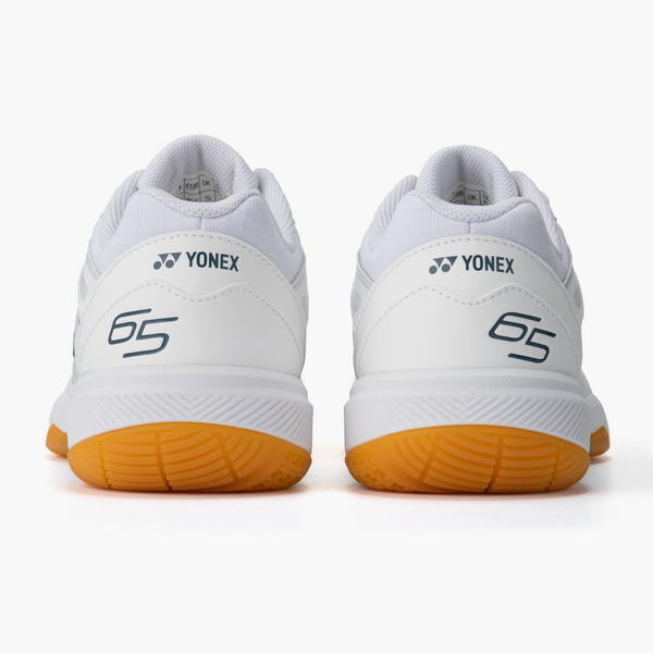 Pair of white Yonex tennis shoes with orange outsole, viewed from the back.