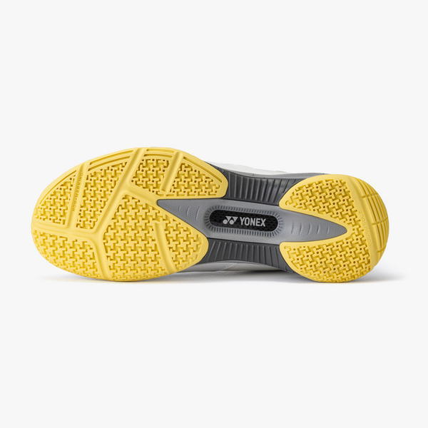 Bottom view of a Yonex athletic shoe sole with a yellow outsole and gray midsole.