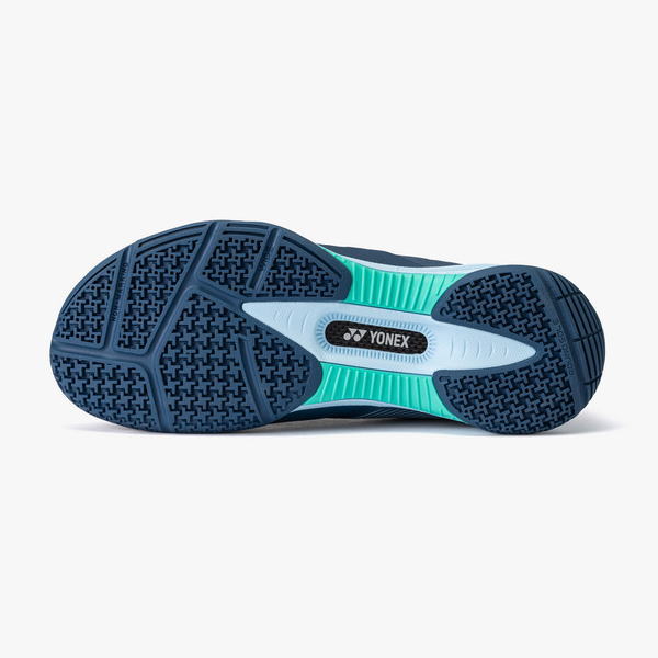 Bottom view of a Yonex athletic shoe showing a blue outsole with textured tread and teal midsection.