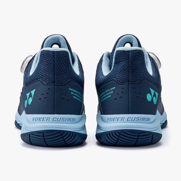 Pair of dark blue athletic shoes with light-blue accents, viewed from the back showing Power Cushion on the heel and turquoise brand logos