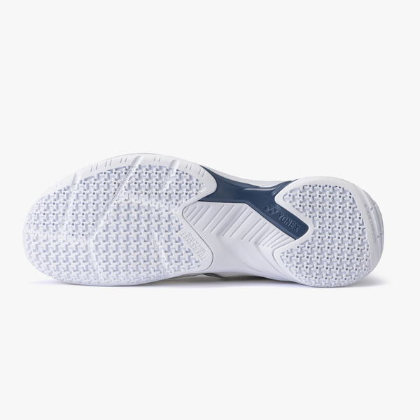 Bottom view of a white athletic shoe outsole with textured grip patterns and a dark blue midfoot support labeled Yonex.