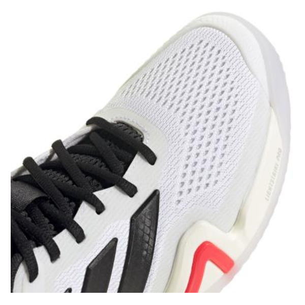 White athletic shoe with black laces and subtle orange/pink sole accent, photographed from top-left.