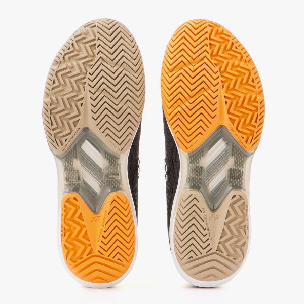 Pair of athletic sneakers shown from the bottom; left sole beige with herringbone tread, right sole orange with similar pattern and a clear midfoot support section