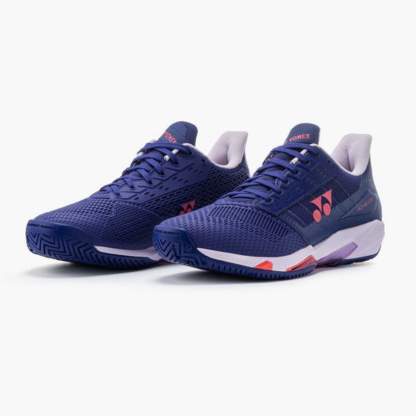 Pair of dark blue Yonex athletic sneakers with pink logos and white midsoles on a white background.