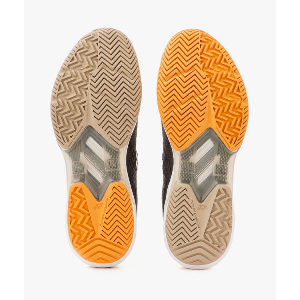 Bottom view of two athletic shoes, beige and orange outsole patterns visible on each sole.