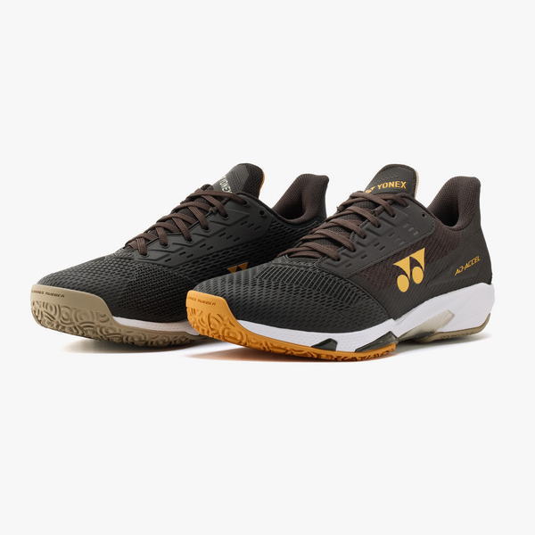 Pair of black Yonex badminton shoes with orange outsole accents and yellow logo on the side.