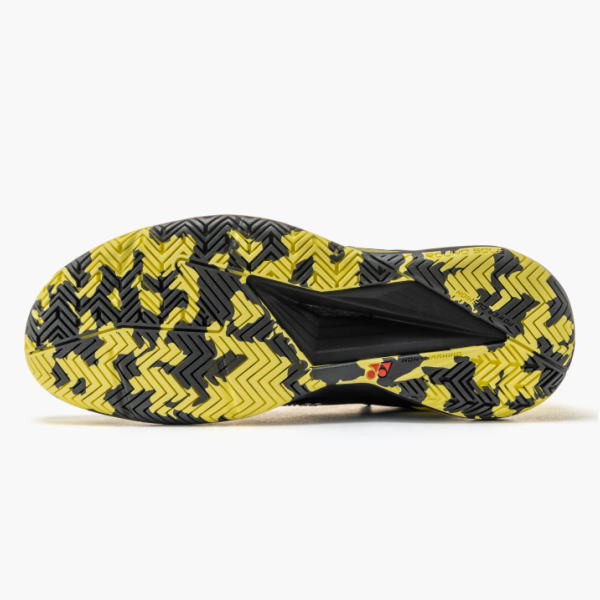 Outsole of a yellow and black zigzag traction shoe with deep grooves visible from the bottom view,