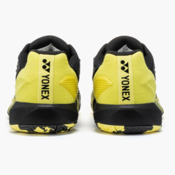 Rear view of bright yellow Yonex badminton shoes with black heel and sole.