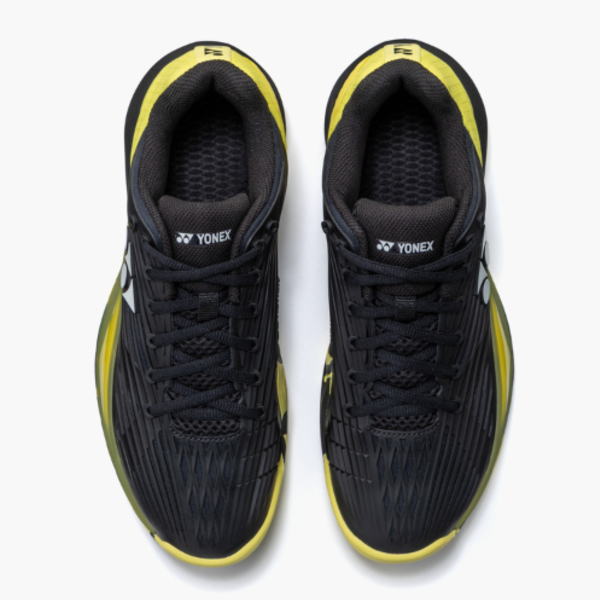 Top-down view of a pair of black Yonex athletic shoes with yellow accents, laced and ready to wear.